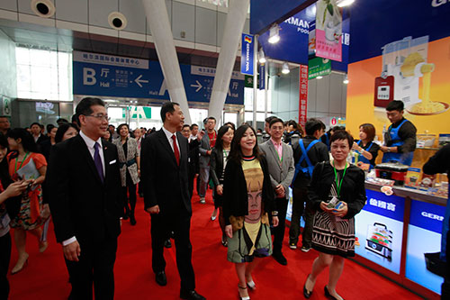 香港特区政府驻北京办事处驻京办主任朱曼铃陪同苏锦梁及黑龙江省副省长孙尧巡视工展会内摊位